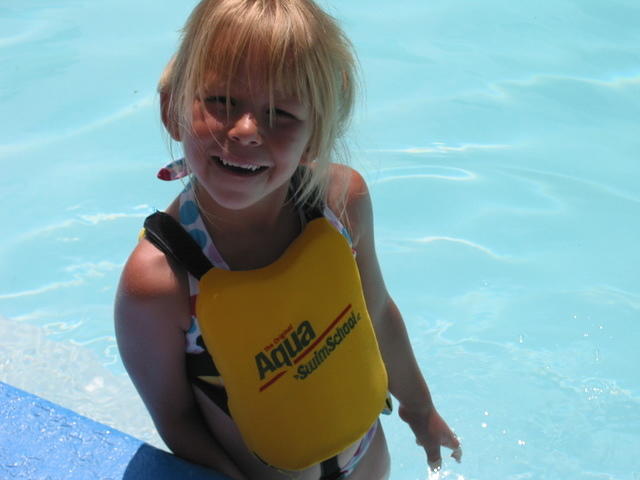 Carrie standing on a seat along the edge of the pool