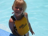 Carrie standing on a seat along the edge of the pool